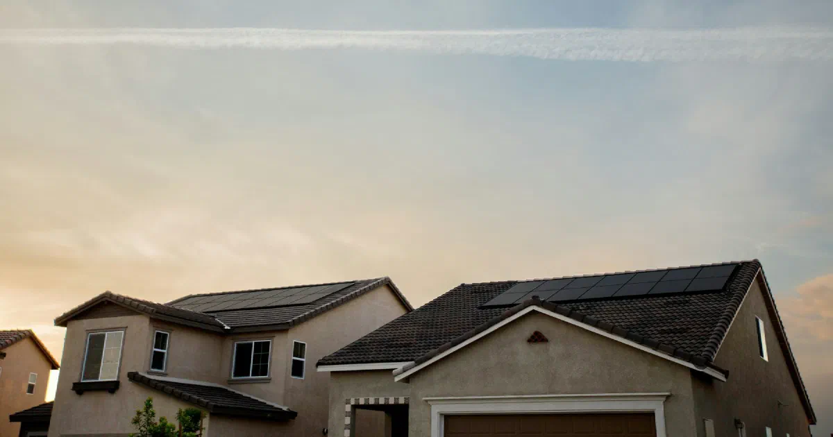 Suburban homes at dusk with solar panels on a tile roof.