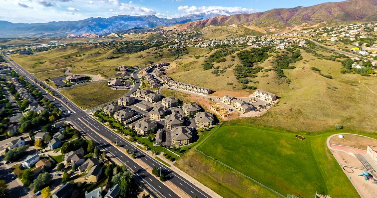 Aerial view of a Colorado Springs neighborhood and highway with mountains in the distance.