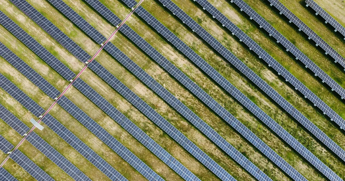 Aerial view of rows of solar panels across a grassy field.