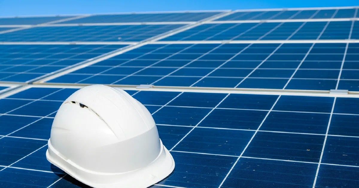 White hard hat resting on a blue solar panel array.
