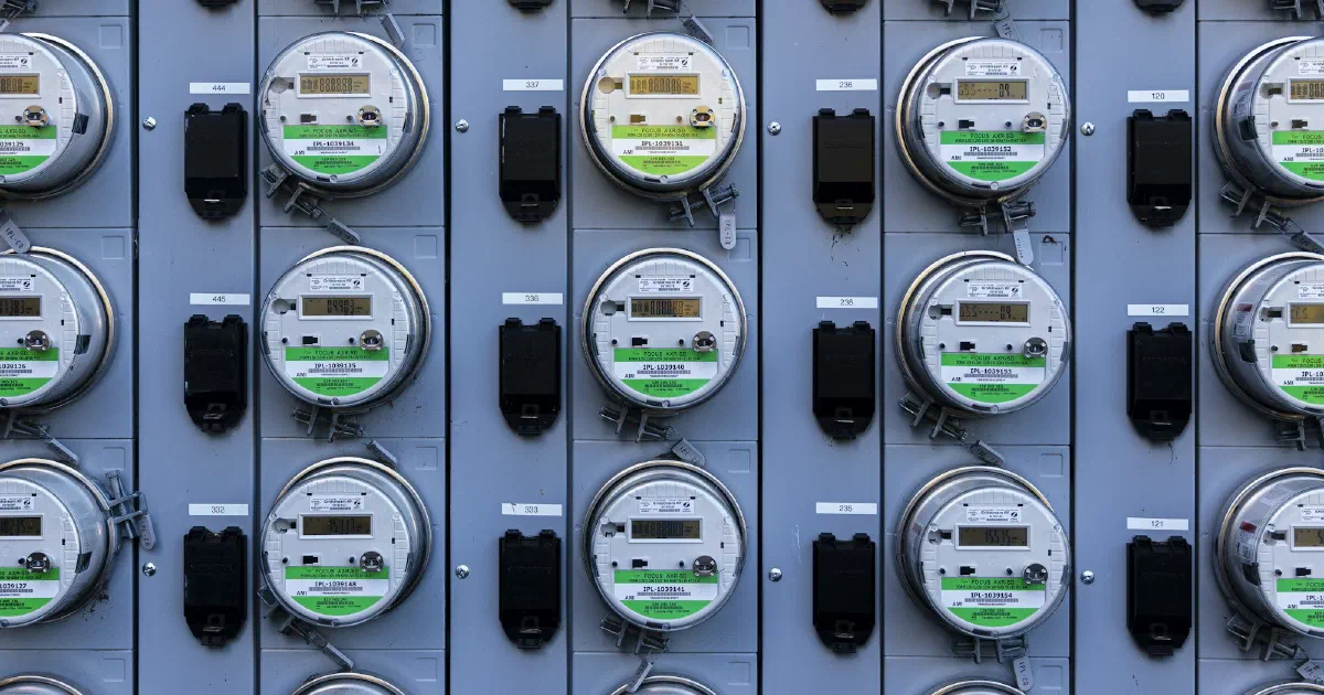 Rows of round electric meters mounted on a gray metal panel.