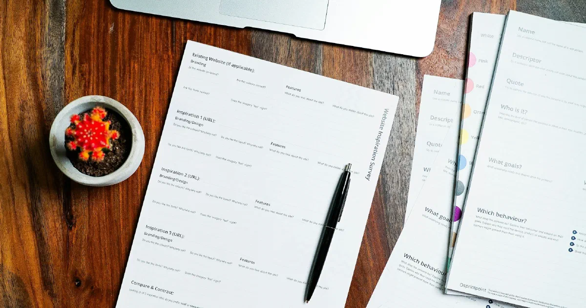 Printed forms and a pen spread across a dark wooden table.