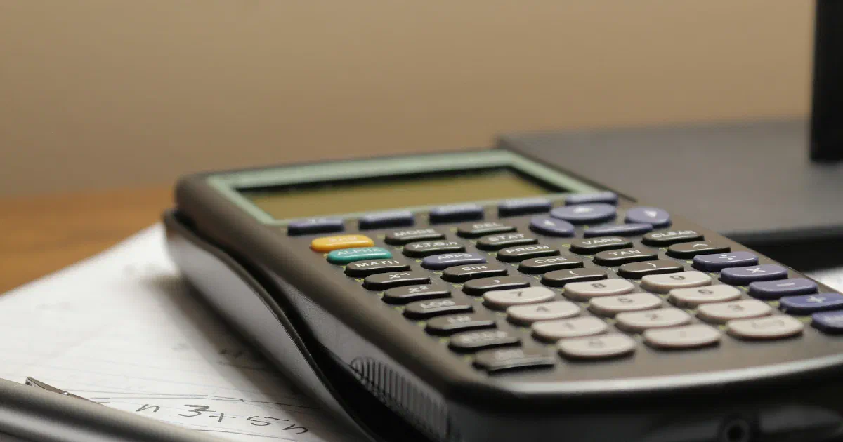 Calculator and mechanical pencil resting on a page of handwritten math.