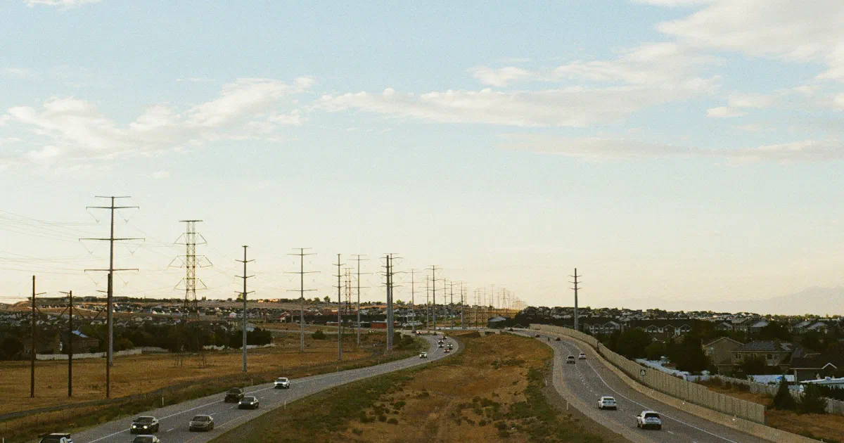 Highway through dry open country with a line of power poles alongside.