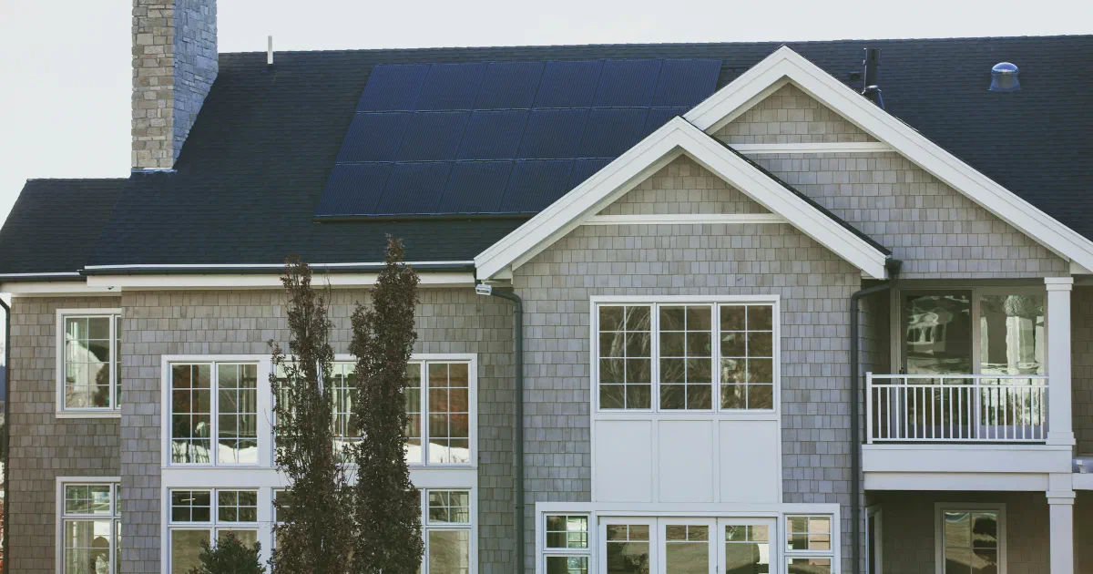 Large gray house with a dark solar panel section on its roof.
