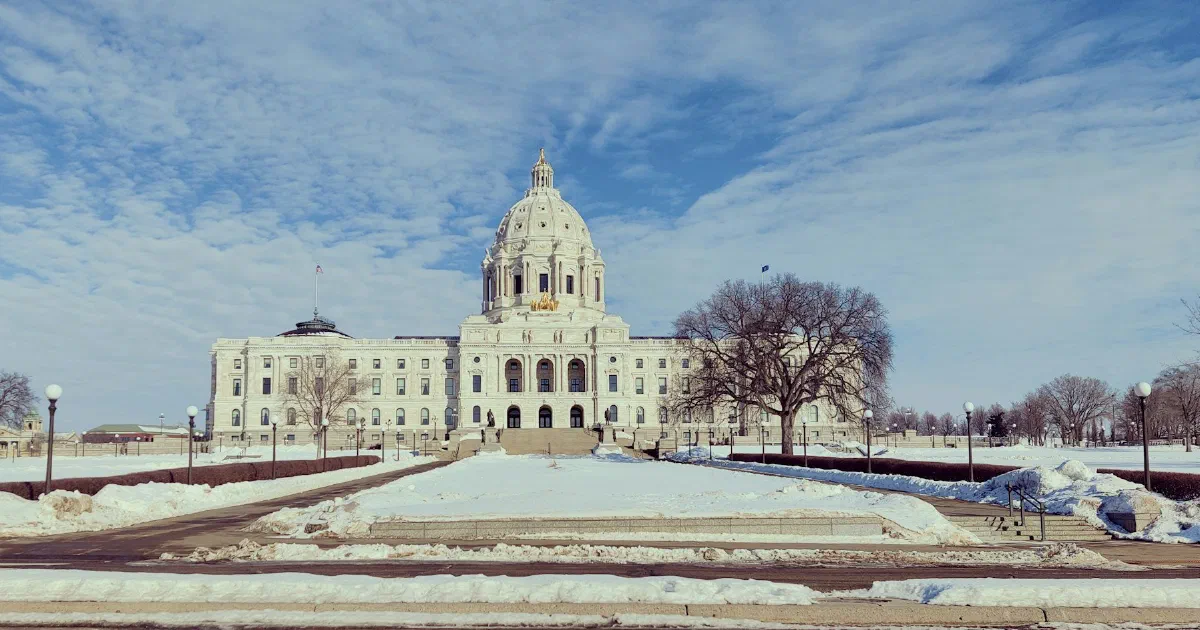 Minnesota State Capitol in St. Paul with snow on the grounds under a blue sky.