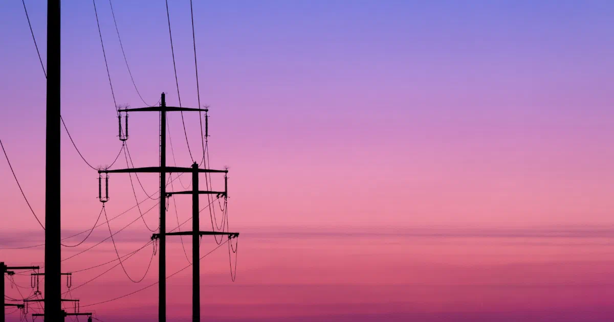 Power poles and lines silhouetted against a pink and violet dusk sky.