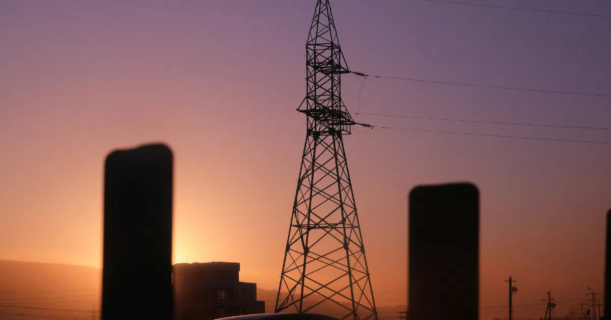 Transmission tower silhouetted against a purple and orange dusk sky.