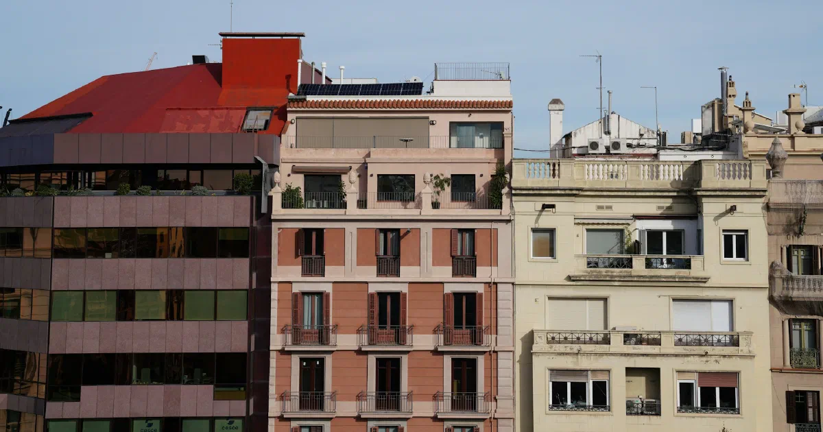 Row of apartment buildings against a clear sky, with a small solar panel array on one rooftop.