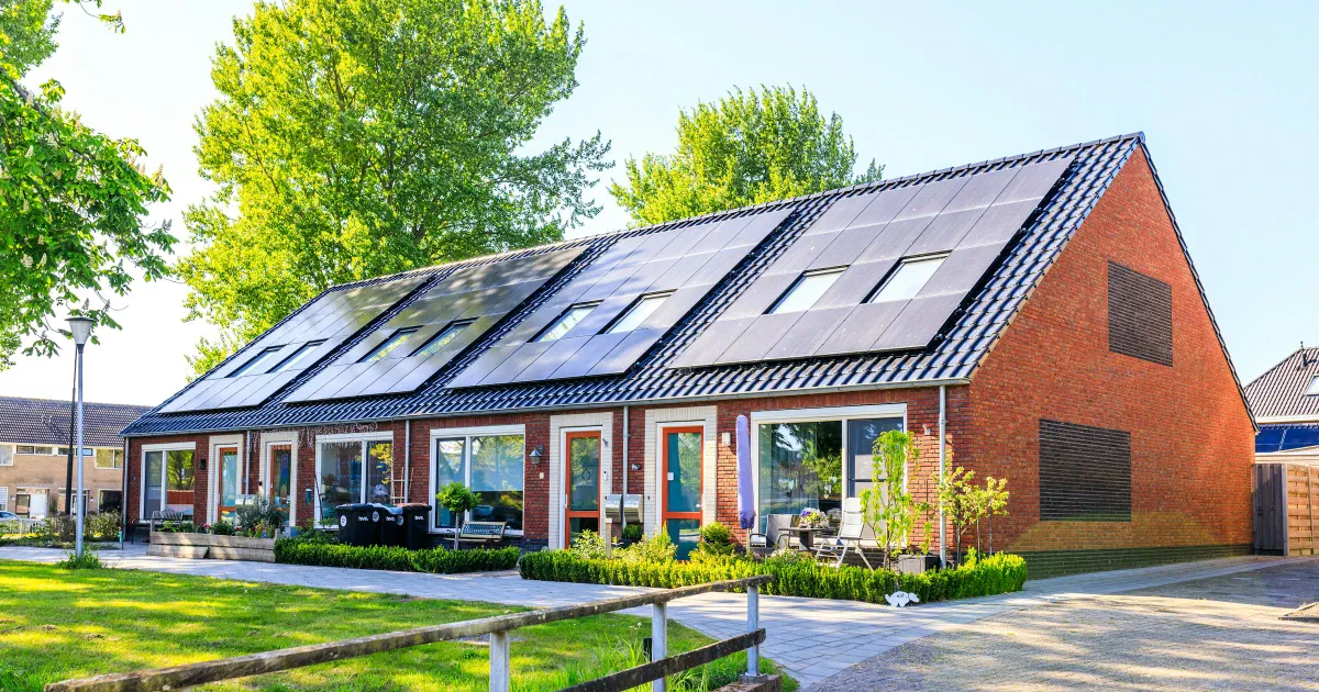 Row of brick houses with solar panels covering the dark roofs.